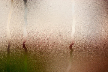 Texture of the rain on the window glass. Illuminated background.