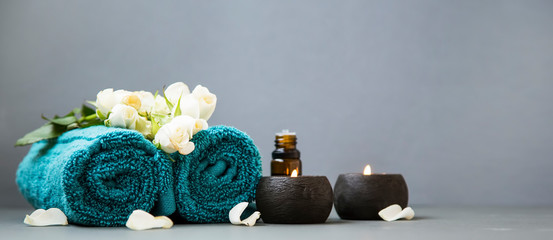 Spa still life with candles, towels and flowers on grey background copy space - obrazy, fototapety, plakaty