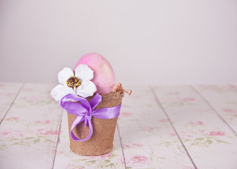 Naklejka premium Easter pink egg in a pot on the floral background