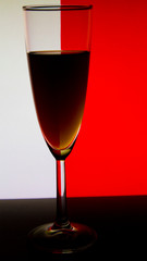 Glass or stemware with alcohol wine,whiskey,gin,beer,rum,vodka,Scotch,cognac,liquor,brandy,absinthe or cocktail on white red background. A glass on the bar in a cafe, restaurant, nightclub or disco.