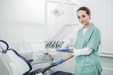 beautiful dentist smiling while gesturing in dental clinic