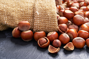 Hazelnut  in burlap sack on black table.