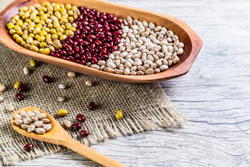 Variety of beans on wooden spoon on wooden background. mung beans, peanuts, red beans and brown beans.