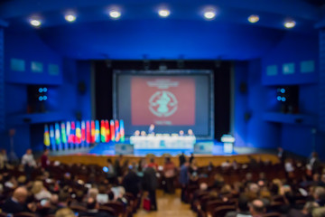 Defocused image. People in the auditorium. International conference. Flags of different countries...
