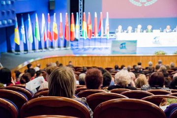 Defocused image. People in the auditorium. International conference. Flags of different countries...
