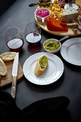 Antipasti board with cheese and meat snacks with red wine and baguette on board on black table
