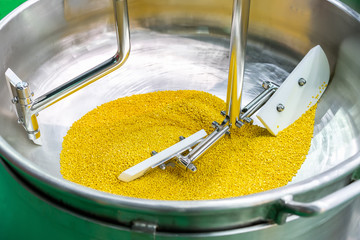 Close up flat beater and raw material inside barrel of commercial food mixer machine for industrial (during stir soybean seeds)