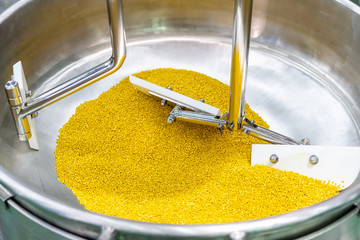 Close up flat beater and raw material inside barrel of commercial food mixer machine for industrial (during stir soybean seeds)