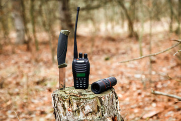 axe, monocle, tourist knife and radio set on the stump in autumn forest