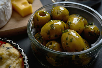 Close up on glass bowl with olives with parsley on black table
