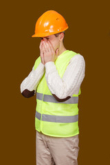 the man in a construction helmet and a vest sneezes