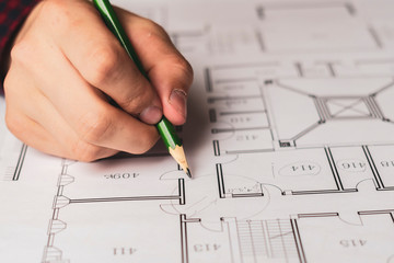 engineer sketching building project on a blueprint with a pencil b
