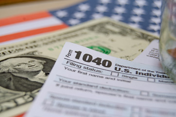 jar with coins and dollar inside with mark tax on it, 1040 form and usa flag