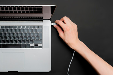 persons hand insert usb wire in a laptop isolated b