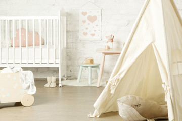 Fototapeta na wymiar Tent, crib and kids furniture in the nursery room, nicely decorated kids room