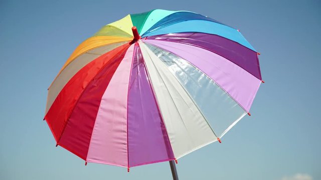 Frame-by-frame video shooting: Multicolored umbrella is spinning. Sky background