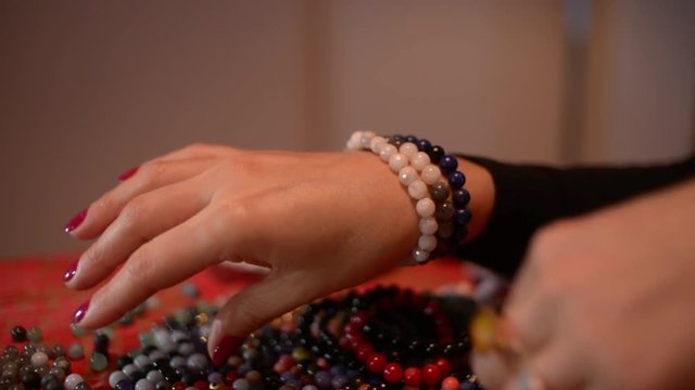 Women's hands measure Coral Bracelets on a Table