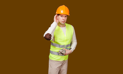 the man in a construction helmet, a vest laid a hand to an ear better to hear