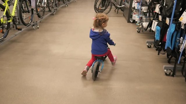 Little Girl Kid trying to ride a Bicycle on a Sports Store