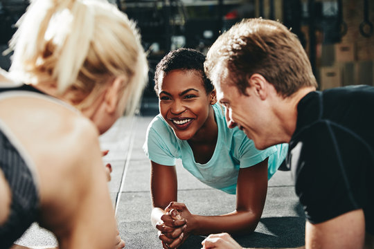 Diverse friends smiling while planking together during a gym cla