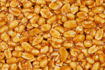 Kozinaki from golden, roasted peanuts beans as a background, texture. Macro shooting, close-up. Place for text