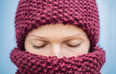 Portrait of a woman dressed in a burgundy knitted hat and scarf close-up