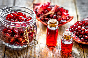 sliced pomegranate and extract in glass on wooden background