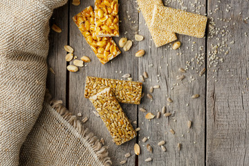 Assorted kozinaki, on old vintage background, with burlap fabric. Country style. Delicious sweets from the seeds of sunflower, sesame and peanuts, covered with shiny glaze.