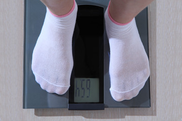 Human stands on an electronic scale.