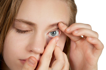 A young girl inserts contact lenses into her eyes.