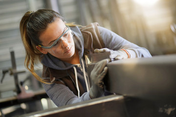 Woman apprentice training in metalwork workshop