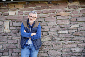 Man standing and leaning on stone wall