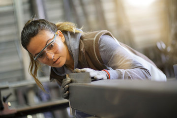 Woman apprentice training in metalwork workshop - obrazy, fototapety, plakaty