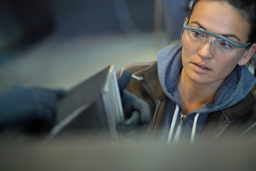 Young woman aprentice in ironwork workshop