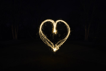 heart shape light painting with sparklers outdoors at night - symbol for love and romance