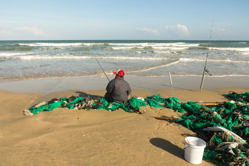 Obraz premium A Fisherman sitting and fishing on Seashore