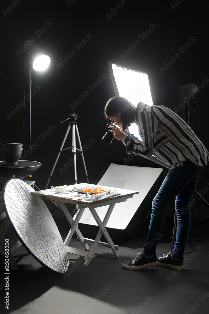 Wall mural young woman taking picture of tasty pasta in professional photo studio