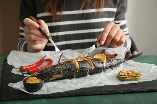 Woman Eating Tasty Mackerel Fish At Table, Closeup