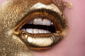 Golden girl. Paint golden on woman face. Provocative makeup. Glamorous life. Expensive cosmetics. Rich woman. Gold concept. Mat lips, white teeth. Makeup artist concept. Beauty saloon. Fashion show.