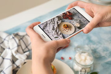 Female food photographer with mobile phone taking picture of tasty cake, closeup