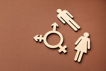 Female and male figures with symbol of transgender on color background