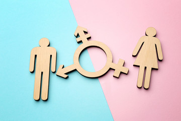 Female and male figures with symbol of transgender on color background