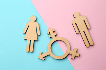 Female and male figures with symbol of transgender on color background