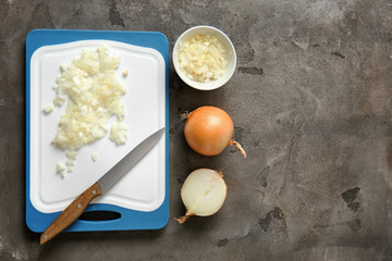 Cutting board with raw onion on grey background