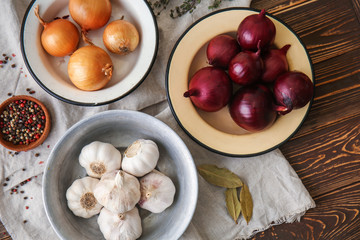 Bowls with raw onion and garlic on table
