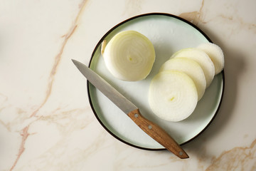 Plate with cut onion and knife on light table