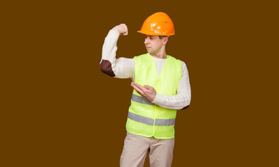 the man in a construction helmet, a vest shows hand biceps force, having bent in an elbow