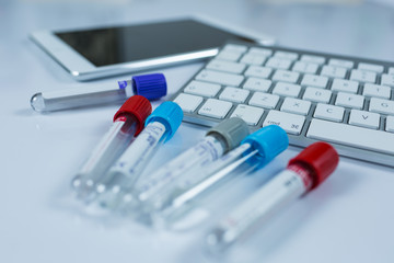 Medicine bottles for samples next to computer tablet and computer keyboard in medicine, closeup on white background