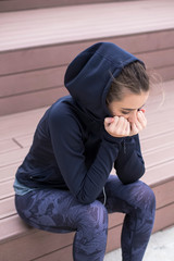 Worried, sad and depressing young woman sits outside