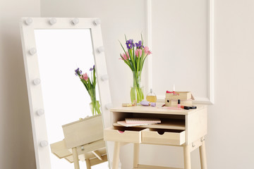 Table with set of decorative cosmetics in room